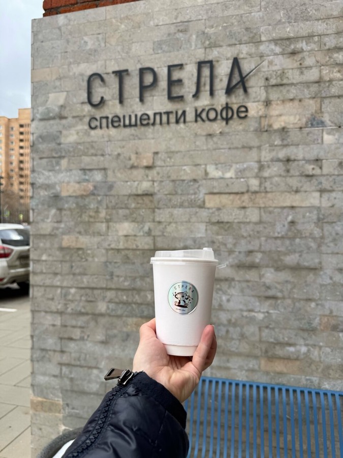 Стакан кофе на фоне вывески «Стрела»